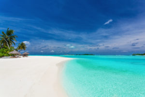 crystal blue waters on sandy white beaches with clear blue skies and clouds and palm trees